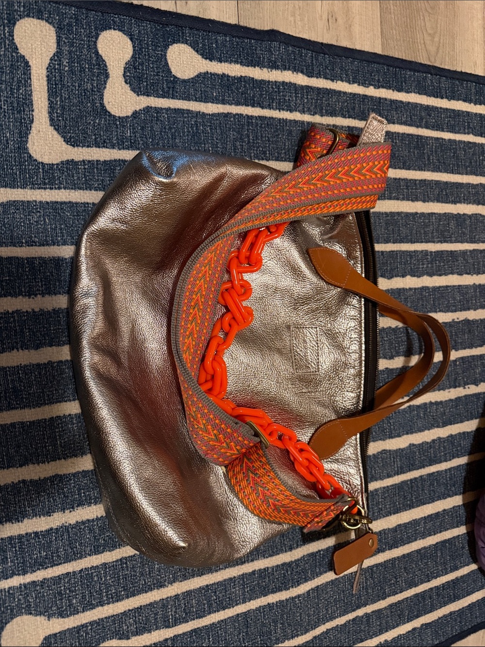 Metallic Silver Shoulder Bag with Orange Accent Strap and Brown Handles